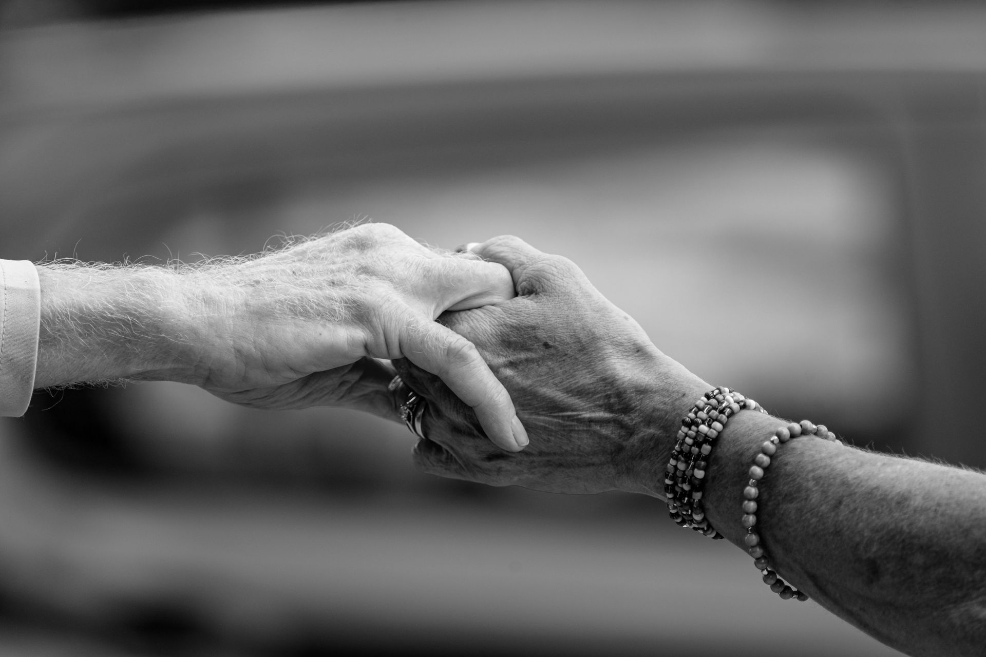 A close-up black and white image of two hands holding, symbolizing connection and support.